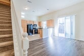 This two-story home offers a thoughtfully designed layout that balances functionality and comfort throughout. The main level centers around an open-concept kitchen and living area, where wood-look flooring flows seamlessly toward a sliding glass door that opens to an outdoor patio. The kitchen is well-equipped with light maple cabinetry, granite countertops, a double-basin stainless steel sink, and black appliances including a gas range, built-in microwave, refrigerator, and dishwasher. Vaulted ceilings in the kitchen lend a sense of openness and airiness to the space. A staircase with a classic white baluster railing connects the main level to the upper floor, where the bedrooms are located. The carpeted bedrooms are generously sized and receive ample natural light through large windows. One bedroom features a walk-in closet with built-in shelving and hanging rods. The primary bathroom is a standout, offering dual sinks set in granite countertops, a separate glass-enclosed shower, a soaking tub, and wood-look flooring. A dedicated laundry area houses a full-size washer and dryer beneath overhead cabinetry for added storage. Throughout the home, neutral tones and consistent finishes create a cohesive and welcoming atmosphere.