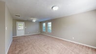 This single-story, 2-bedroom, 1-bathroom home offers a straightforward and functional layout across one level. The spacious primary bedroom is notably generous in size, featuring soft carpet flooring, neutral beige walls, a ceiling fan with light fixture, and multiple windows fitted with blinds that allow ample natural light to fill the room. The second bedroom mirrors a similar design with carpeted floors, a ceiling fan, and a window overlooking the outdoors, providing a comfortable and well-lit space. The kitchen is outfitted with warm-toned wood cabinetry, blue-speckled countertops, and light hardwood-style flooring, creating a practical and organized cooking area. A dedicated utility room and closet add to the home's functional appeal. The full bathroom features a clean, white tub-shower combination with a chrome grab bar, maintaining a simple and utilitarian aesthetic. Throughout the home, textured ceilings and neutral-toned walls provide a consistent, understated backdrop. Ceiling fans are present in key rooms, enhancing comfort year-round. The overall ambiance is clean, bright, and move-in ready, making it a practical and comfortable living space.