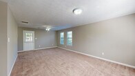 This single-story, 2-bedroom, 1-bathroom home offers a straightforward and functional layout across one level. The spacious primary bedroom is notably generous in size, featuring soft carpet flooring, neutral beige walls, a ceiling fan with light fixture, and multiple windows fitted with blinds that allow ample natural light to fill the room. The second bedroom mirrors a similar design with carpeted floors, a ceiling fan, and a window overlooking the outdoors, providing a comfortable and well-lit space. The kitchen is outfitted with warm-toned wood cabinetry, blue-speckled countertops, and light hardwood-style flooring, creating a practical and organized cooking area. A dedicated utility room and closet add to the home's functional appeal. The full bathroom features a clean, white tub-shower combination with a chrome grab bar, maintaining a simple and utilitarian aesthetic. Throughout the home, textured ceilings and neutral-toned walls provide a consistent, understated backdrop. Ceiling fans are present in key rooms, enhancing comfort year-round. The overall ambiance is clean, bright, and move-in ready, making it a practical and comfortable living space.
