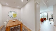 Located along Santa Monica Boulevard in the heart of Los Angeles, this modern 2-bedroom, 1-bathroom residence offers a thoughtfully designed layout with clean lines and contemporary finishes throughout. Light wood flooring flows through the open-plan living and dining areas, complemented by recessed lighting and crisp white walls that create a bright, airy ambiance. The living room is anchored by floor-to-ceiling sliding glass doors that open onto a private balcony, framing sweeping views of the surrounding cityscape and filling the space with abundant natural light. The kitchen is outfitted with sleek white cabinetry, a tile backsplash, stainless steel appliances, a built-in wine refrigerator, and a peninsula with bar seating — ideal for both everyday living and entertaining. The spacious primary bedroom features direct balcony access through glass sliding doors, plush carpeting, and generous proportions. The second bedroom is well-sized with soft carpet and ample wall space. The bathroom is finished in neutral tones with large-format tile flooring, a floating vanity, and a frameless glass walk-in shower. A connecting hallway ties the layout together seamlessly, making this residence as functional as it is stylish.