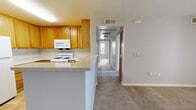 Located at 5 Hathaway Dr in Novato, CA, this single-floor, 2-bedroom, 1-bathroom home offers a practical and comfortable layout. The combined kitchen and living area forms the heart of the home, with the kitchen featuring warm honey-toned oak cabinetry, light-toned countertops, a gas range with over-the-range microwave, and a full-size refrigerator. A peninsula counter provides additional prep space and separates the kitchen from the living area. Tile flooring runs through the kitchen and entry, while soft, neutral carpet extends throughout the living room and bedrooms. The spacious living room is highlighted by a sliding glass door that opens to a private balcony with outdoor views, allowing natural light to fill the space. Both bedrooms are carpeted and feature neutral grey walls, with windows framing views of the surrounding greenery. The primary bedroom is generously sized and benefits from multiple windows that invite in ample daylight. The full bathroom includes warm wood-toned cabinetry, a white countertop vanity, a large mirror, and tile flooring. A hallway connects the rooms, creating a clean and functional flow throughout this well-appointed home.