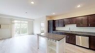 Located at 2290 Anchor Dr in North St. Paul, MN, this well-appointed two-bedroom, two-bathroom residence offers a thoughtfully designed single-level layout. The open-concept kitchen and living area serves as the heart of the home, showcasing rich dark-espresso cabinetry, granite countertops, and a full suite of stainless steel appliances including a range, microwave, and French door refrigerator. A freestanding kitchen island with additional granite surface and built-in shelving provides extra workspace and storage. Light hardwood-style flooring runs throughout the main living areas, complementing the neutral color palette and recessed lighting. The living room benefits from natural light and direct access to a private balcony overlooking a lush, tree-lined setting. Both bedrooms are carpeted and feature large windows with wooded views, ceiling fans, and baseboard heating. The primary bedroom is generously proportioned with its own dedicated closet. The primary bathroom features a double-sink granite vanity with dark cabinetry, while the second bathroom includes a full tub and shower combination. A dedicated in-unit laundry room with side-by-side washer and dryer and overhead shelving adds everyday convenience. Two closets provide ample storage throughout.