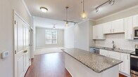 Located at 12000 Sweet Pl in Charleston, SC, this well-appointed 2-bedroom, 2-bathroom residence offers a thoughtfully designed single-floor layout. The open-concept kitchen and living area serves as the heart of the home, showcasing warm hardwood flooring, crown molding, and stylish pendant lighting. The kitchen is equipped with stainless steel appliances, white shaker cabinetry, a subway tile backsplash, and a granite-topped island that provides ample prep space and casual seating. The living area extends naturally from the kitchen, featuring a ceiling fan and a large window that fills the space with natural light and outdoor views.

The spacious primary bedroom features plush carpeting, crown molding, a ceiling fan, and generous windows overlooking greenery. It is complemented by a large walk-in closet with multi-level wire shelving. The second bedroom also offers comfortable carpeting and its own walk-in closet. Both bathrooms are finished with granite-topped vanities and white cabinetry; the primary bath includes a dual-sink vanity and hardwood flooring, while the secondary bath features a tub-shower combination with white tile surround. Throughout, neutral tones and consistent finishes create a clean, cohesive aesthetic.