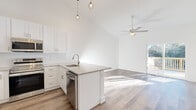 Located at 51 Hillside Rd in Pine Plains, NY, this two-floor home showcases a clean, modern design with consistent finishes throughout. The open-concept kitchen is a standout feature, equipped with white shaker cabinetry, stainless steel appliances, granite countertops, a peninsula with a built-in sink, and stylish pendant lighting. Soaring vaulted ceilings amplify the sense of space in the main living area, which is enhanced by a ceiling fan and a sliding glass door leading to an outdoor deck with views of the surrounding natural landscape. Wide-plank hardwood-style flooring runs throughout the main living spaces, lending warmth and continuity to the home's bright, airy aesthetic. A hallway with high ceilings and a decorative pendant light connects multiple rooms, including closets with wire shelving systems. The bathroom features marble-style tile flooring, a granite-topped white vanity, and clean, minimalist finishes. Bedrooms benefit from vaulted ceilings, ceiling fans, and abundant natural light through well-placed windows. The attached garage offers ample space with a concrete floor and an automatic opener, while the unfinished basement provides significant potential for future customization or additional storage.