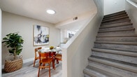 This two-story, two-bedroom, two-bathroom home in Chandler, Arizona offers a well-organized layout spread across two floors of comfortable living space. The main level houses the living room, dining area, and kitchen, while the upper floor accommodates the bedrooms and additional bathrooms. Throughout the home, wood-look luxury vinyl flooring provides a clean, cohesive aesthetic.

The kitchen is a standout feature, boasting crisp white shaker cabinets with matte black hardware, stone-look countertops, a classic white subway tile backsplash, and stainless steel appliances including a range, over-the-range microwave, and dishwasher. A skylight adds natural brightness to the space. The adjacent dining area benefits from a sliding glass door that fills the room with natural light and provides outdoor access.

The living room is a comfortable, neutral-toned space with a large window fitted with vertical blinds. Both bedrooms feature wood-look flooring and ceiling fans, with the primary bedroom offering generous proportions. The two bathrooms are finished with white shaker vanities, stone-look countertops, and matte black fixtures, maintaining a consistent modern aesthetic. A dedicated laundry area is also present. Multiple closets throughout provide ample storage.