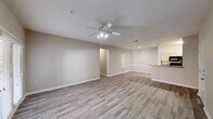 Located at 2931 Barker Cypress Rd in Houston, TX 77084, this single-floor unit offers a clean, modern aesthetic throughout. The open living area is expansive and filled with natural light, showcasing durable wood-look plank flooring, neutral warm-gray walls, and a ceiling fan with integrated lighting. A raised bar counter separates the living space from the galley-style kitchen, which features light wood cabinetry, stone-patterned countertops, black appliances including a refrigerator, range, microwave, and dishwasher, along with a stainless steel sink. The layout flows efficiently, with a front entry door opening directly into the main living zone. The bedrooms continue the wood-look flooring and neutral palette, each equipped with ceiling fans and ample wall space. One bedroom includes access to a walk-in closet. The bathrooms are well-appointed, featuring tub-shower combinations with white tile surrounds, chrome fixtures, and wood-toned vanity cabinetry with solid countertops. Wood-look tile flooring carries through the bathrooms, maintaining a consistent design language. The overall ambiance is bright, clean, and move-in ready, offering a practical and comfortable living environment.