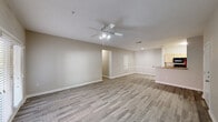 Located at 2931 Barker Cypress Rd in Houston, TX 77084, this single-floor unit offers a clean, modern aesthetic throughout. The open living area is expansive and filled with natural light, showcasing durable wood-look plank flooring, neutral warm-gray walls, and a ceiling fan with integrated lighting. A raised bar counter separates the living space from the galley-style kitchen, which features light wood cabinetry, stone-patterned countertops, black appliances including a refrigerator, range, microwave, and dishwasher, along with a stainless steel sink. The layout flows efficiently, with a front entry door opening directly into the main living zone. The bedrooms continue the wood-look flooring and neutral palette, each equipped with ceiling fans and ample wall space. One bedroom includes access to a walk-in closet. The bathrooms are well-appointed, featuring tub-shower combinations with white tile surrounds, chrome fixtures, and wood-toned vanity cabinetry with solid countertops. Wood-look tile flooring carries through the bathrooms, maintaining a consistent design language. The overall ambiance is bright, clean, and move-in ready, offering a practical and comfortable living environment.