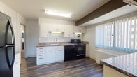Located at The Shoreham in Lakewood, Ohio, this single-floor residence presents a clean, modern aesthetic defined by a consistent two-tone design scheme of crisp white walls accented by bold dark trim and beam details throughout.

The kitchen is well-appointed with white cabinetry extending to the ceiling, granite-style countertops, and wood-look vinyl flooring. Black appliances—including a refrigerator, electric range, and dishwasher—provide a striking contrast against the bright cabinetry. Generous counter and storage space make the kitchen both functional and visually cohesive. A window with vertical blinds allows natural light to filter in.

The living areas are spacious and open, featuring neutral carpet, white walls, and the signature dark architectural accents that carry throughout the unit. The layout flows naturally between the main living space and adjoining rooms, with hard-surface flooring in the transition areas.

The bedrooms are carpeted and generously sized, each featuring windows with vertical blinds and closet access. The two bathrooms are finished with tile flooring, dark vanity cabinetry, and white countertops. One bathroom includes a tub-shower combination, while the other features a walk-in shower with sliding glass doors—offering practical variety for residents.