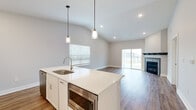 Located at 24 Bay Front Dr in Traverse City, Michigan, this contemporary two-floor home blends modern design with functional living. The main level showcases an open-concept layout with vaulted ceilings that lend an airy, expansive feel. The kitchen is a standout, featuring white shaker cabinetry, crisp quartz countertops, a large center island with a built-in sink and microwave, stainless steel appliances including a gas range and refrigerator, a stylish hood vent, and a tile backsplash. Pendant lighting illuminates the island, adding a refined touch. The kitchen flows seamlessly into the living area, which features warm hardwood-style flooring, a fireplace, and sliding glass doors that open to an outdoor deck, inviting natural light throughout. Bedrooms on the main level are finished with vaulted ceilings and hardwood-style flooring, while additional carpeted bedrooms offer comfortable, quiet retreats with pleasant outdoor views. A full bathroom on this level is outfitted with white cabinetry, quartz counters, and a tub-shower combination. The lower level provides generous carpeted living space with sliding door access to the outdoors, recessed lighting, and an unfinished utility area offering ample storage or future customization potential. Throughout, neutral tones and clean finishes create a cohesive, move-in-ready aesthetic.