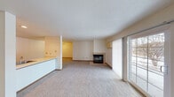 This single-floor residence offers a thoughtfully laid-out interior with a comfortable, neutral aesthetic throughout. The spacious living room serves as the heart of the home, highlighted by a tile-surround fireplace and a sliding glass door fitted with vertical blinds that invite natural light and provide direct access to the outdoors. Soft carpeting extends through the main living and bedroom areas, contributing to a warm, inviting atmosphere.

The kitchen is well-equipped with warm oak cabinetry, light countertops, and a full suite of black appliances including a refrigerator, electric range, and dishwasher. Tile flooring runs through the kitchen and dining area, which features a ceiling fan and an adjacent sink peninsula. A pass-through counter connects the kitchen to the living space, enhancing the open flow of the layout.

The bedrooms are generously sized with plush carpeting, white blinds, and ample closet space, including double closets visible from the hallway. Two bathrooms serve the unit — one featuring a full tub/shower combination with tile flooring, and a second half bath. A dedicated in-unit laundry room provides added convenience, complete with overhead wire shelving for storage. The overall design is clean, functional, and move-in ready.