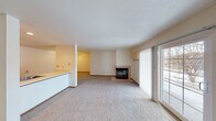 This single-floor residence offers a thoughtfully laid-out interior with a comfortable, neutral aesthetic throughout. The spacious living room serves as the heart of the home, highlighted by a tile-surround fireplace and a sliding glass door fitted with vertical blinds that invite natural light and provide direct access to the outdoors. Soft carpeting extends through the main living and bedroom areas, contributing to a warm, inviting atmosphere.

The kitchen is well-equipped with warm oak cabinetry, light countertops, and a full suite of black appliances including a refrigerator, electric range, and dishwasher. Tile flooring runs through the kitchen and dining area, which features a ceiling fan and an adjacent sink peninsula. A pass-through counter connects the kitchen to the living space, enhancing the open flow of the layout.

The bedrooms are generously sized with plush carpeting, white blinds, and ample closet space, including double closets visible from the hallway. Two bathrooms serve the unit — one featuring a full tub/shower combination with tile flooring, and a second half bath. A dedicated in-unit laundry room provides added convenience, complete with overhead wire shelving for storage. The overall design is clean, functional, and move-in ready.