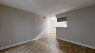 Located at 7703 Seton Lake Dr in Houston, TX, this efficient one-bedroom, one-bathroom unit offers a well-organized single-floor layout. The open-concept living and dining area is finished with warm wood-look tile flooring and neutral gray walls, creating a clean, modern aesthetic throughout. A pass-through counter connects the living space to the galley-style kitchen, which features gray cabinetry, light quartz-style countertops, a stainless steel sink, and black appliances including a range and refrigerator — maximizing both function and style in a compact footprint. The living area is brightened by a large sliding glass door fitted with vertical blinds, providing access to an outdoor patio and allowing natural light to fill the space. The bedroom offers a ceiling fan with light fixture, a window with blinds, and a closet, providing comfortable and practical accommodations. The bathroom is outfitted with a full tub-and-shower combination featuring white tile surround and chrome fixtures, maintaining the unit's clean, neutral palette. Wood-look tile flooring carries consistently throughout, unifying the space with a cohesive and easy-to-maintain finish.