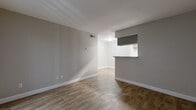 Located at 7703 Seton Lake Dr in Houston, TX, this efficient one-bedroom, one-bathroom unit offers a well-organized single-floor layout. The open-concept living and dining area is finished with warm wood-look tile flooring and neutral gray walls, creating a clean, modern aesthetic throughout. A pass-through counter connects the living space to the galley-style kitchen, which features gray cabinetry, light quartz-style countertops, a stainless steel sink, and black appliances including a range and refrigerator — maximizing both function and style in a compact footprint. The living area is brightened by a large sliding glass door fitted with vertical blinds, providing access to an outdoor patio and allowing natural light to fill the space. The bedroom offers a ceiling fan with light fixture, a window with blinds, and a closet, providing comfortable and practical accommodations. The bathroom is outfitted with a full tub-and-shower combination featuring white tile surround and chrome fixtures, maintaining the unit's clean, neutral palette. Wood-look tile flooring carries consistently throughout, unifying the space with a cohesive and easy-to-maintain finish.