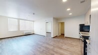 This 2-bedroom, 1-bathroom unit offers a thoughtfully designed single-level layout with a clean, modern aesthetic throughout. Wood-style plank flooring extends seamlessly across every room, lending a warm and cohesive feel to the space.

The open kitchen is outfitted with light wood cabinetry, granite-style countertops, and a full suite of black appliances including a refrigerator, electric range, over-the-range microwave, and dishwasher. The adjacent living room provides a comfortable gathering area with natural light from a large window and a wall-mounted HVAC unit for climate control.

Both bedrooms feature neutral toned walls, wood-style flooring, and individual thermostat controls. The primary bedroom includes a walk-in closet with built-in shelving, offering generous storage. The second bedroom is equally bright and well-proportioned.

The bathroom is finished with a wood-toned vanity, granite-style countertop, a large mirror, and wood-look tile flooring. A dedicated laundry room houses a full-size front-loading washer and dryer with overhead wire shelving, adding everyday convenience.

The unit's clean lines, consistent finishes, and practical layout make it a functional and comfortable living space.