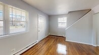 Located at 134 Ridgewood Ave in Pleasantville, NJ, this two-story home offers a clean, straightforward layout with consistent design elements throughout. Rich, warm-toned hardwood flooring runs across both floors, adding character and continuity to the space. The main level features an open entryway with a staircase leading to the upper floor, connecting to a hallway that provides access to the living areas. The kitchen is equipped with warm oak cabinetry, dark granite-style countertops, and a gas range, offering ample storage and functional workspace. A full bathroom on the upper level features a white tub-shower combination, a vanity, and durable vinyl plank flooring. Multiple bedrooms are distributed across both floors, each finished with the same hardwood flooring and neutral light-gray walls. Several bedrooms benefit from multiple windows, allowing natural light to filter in throughout the day. Baseboard heating is present in the rooms, ensuring efficient climate control. The overall aesthetic is clean and neutral, with white trim, panel-style doors, and soft lighting creating a bright, livable environment throughout the home.