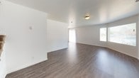 This two-floor residence offers a practical and well-organized layout designed for comfortable everyday living. The main level features a spacious, open living area finished with durable wood-style flooring that extends throughout, allowing natural light to flow in through large windows fitted with blinds. The kitchen is efficiently designed with light wood cabinetry extending to the ceiling for ample storage, a peninsula counter that provides additional workspace, stainless steel appliances including an electric range, over-the-range microwave, refrigerator, and a stainless steel sink. A full bathroom on this level includes a tub-shower combination, a single-sink vanity with neutral stone-tone countertops, and wood-style flooring. The upper level hosts multiple bedrooms, each carpeted in neutral tones and illuminated by natural light through window panels with blinds. One bedroom features dual closet doors, while a hallway area offers generous additional storage with a double closet and separate door access. A second full bathroom on this level mirrors the first in its clean, functional design. Throughout the space, a consistent neutral palette of whites and warm wood tones creates a clean, move-in ready environment.