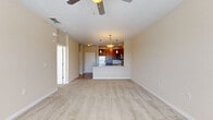 Located at 10207 Dwell Court in Orlando, FL, this one-bedroom, one-bathroom residence offers a well-designed single-floor layout that maximizes functionality and comfort. The open-concept living and kitchen area serves as the heart of the home, where plush carpeting in the living space transitions to clean tile flooring in the kitchen. The kitchen is outfitted with rich dark wood cabinetry, granite countertops, a tile backsplash, and a full suite of stainless steel appliances including a refrigerator, range, microwave, and dishwasher. A peninsula with an integrated sink and pendant lighting above adds both practicality and style, creating a natural divide between cooking and living spaces. Ceiling fans provide comfort throughout. The bedroom is a well-proportioned retreat featuring a bank of three windows that invite abundant natural light and views of the surrounding greenery. Soft carpeting and neutral warm tones create a calm atmosphere. The bedroom connects to a spacious walk-in closet with wire shelving on multiple walls, offering generous storage. The bathroom features large-format tile flooring, a dark wood vanity with a granite top, and a full tub-shower combination, completing this thoughtfully appointed residence.