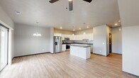 Located at 300 Devitt Dr in Harrisburg, SD, this two-story home offers a well-organized layout spread across two floors. The main level opens into a combined kitchen and living area, where light wood-look flooring flows throughout. The kitchen is a standout feature, showcasing white shaker cabinets, dark granite countertops, a central island, stainless steel appliances including a French door refrigerator and range, and pendant lighting that complements the recessed ceiling lights. A ceiling fan overhead serves the open living area adjacent to the kitchen. A dedicated laundry room on the main level provides added convenience, complete with a full-size washer and dryer setup. The attached garage offers generous space with an automatic opener and drywall-finished interior. A carpeted staircase connects the two levels, leading to the upper floor where the three bedrooms are located. The spacious primary bedroom is accompanied by its own bathroom, featuring granite-topped vanity and a bathtub. Each bedroom includes its own closet with built-in shelving and hanging rods. The secondary bedrooms feature carpet flooring, large windows for natural light, and neutral-toned walls. Three full bathrooms and two hallways complete the functional and practical floor plan of this Harrisburg home.