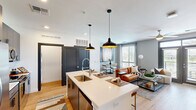 Located at 1000 North 44th Street in Phoenix, AZ, this well-appointed one-bedroom, one-bathroom residence offers a thoughtfully designed open-concept layout with modern finishes throughout. Light wood-style flooring flows seamlessly through the main living areas, creating a bright and cohesive aesthetic.

The kitchen serves as the heart of the home, anchored by a large center island with a white quartz countertop and seating for multiple guests. Dark cabinetry, stainless steel appliances, a professional-style faucet, and dual pendant lights overhead complete the contemporary look. The kitchen opens directly to the combined dining and living area, where large windows and French doors flood the space with natural light and provide access to a private balcony with outdoor views.

The bedroom is a calm retreat featuring plush carpeting, a ceiling fan, a large window with palm tree views, and direct access to a spacious walk-in closet outfitted with multi-level shelving and hanging rods. The full bathroom offers a clean, modern design with a tiled shower-tub combination, gray vanity cabinetry, and white countertops. An in-unit laundry area adds practical convenience to this well-rounded Phoenix residence.