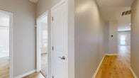 This single-story home is designed with an open-concept floor plan that creates a seamless flow between the living, dining, and kitchen areas. Light hardwood flooring extends throughout the main living spaces, complemented by neutral gray-toned walls and crisp white trim, lending the interior a clean, contemporary aesthetic. A chandelier accent and recessed lighting illuminate the open living and dining area, while a large window allows natural light to filter in.

The kitchen is well-appointed with white shaker-style cabinetry featuring gold-toned hardware, granite countertops, and a full suite of stainless steel appliances, including a range, over-the-range microwave, and French door refrigerator. A central island with a built-in sink provides additional workspace and casual seating potential.

The bedrooms are carpeted for comfort, each featuring ceiling fans, ample natural light from slatted-blind windows, and neutral wall tones. A hallway with angled ceiling details connects the private quarters to the main living areas.

The bathrooms are finished with granite-topped white vanities with gold hardware. One bathroom features a tub-shower combination with brushed nickel fixtures and hardwood-style flooring, maintaining cohesion with the rest of the home's design palette.