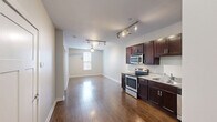 Located at 805 Canal St in Chattanooga, Tennessee, this one-bedroom, one-bathroom unit offers a well-designed layout that makes excellent use of its compact footprint. The kitchen serves as a standout feature, showcasing rich dark wood cabinetry with sleek hardware, light granite countertops, and a full suite of stainless steel appliances including a range, microwave, dishwasher, and refrigerator. Track lighting overhead and warm hardwood flooring complete the kitchen's polished, functional aesthetic. The open layout visible from the kitchen extends into the main living area, also finished in hardwood floors, creating a cohesive and inviting flow throughout the common spaces. The bedroom is carpeted for comfort, finished in neutral tones, and features an exterior door with a glass panel that brings in natural light and provides outdoor access. The bathroom is clean and modern, with large-format tile flooring, a dark wood vanity topped with granite, and brushed nickel fixtures. Conveniently adjacent to the bathroom is a dedicated closet with built-in shelving and hanging rods, providing practical storage. The overall color palette throughout the unit is light and neutral, lending the space a bright, move-in-ready feel well-suited for urban living in Chattanooga.