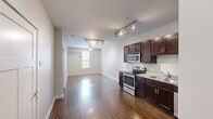 Located at 805 Canal St in Chattanooga, Tennessee, this one-bedroom, one-bathroom unit offers a well-designed layout that makes excellent use of its compact footprint. The kitchen serves as a standout feature, showcasing rich dark wood cabinetry with sleek hardware, light granite countertops, and a full suite of stainless steel appliances including a range, microwave, dishwasher, and refrigerator. Track lighting overhead and warm hardwood flooring complete the kitchen's polished, functional aesthetic. The open layout visible from the kitchen extends into the main living area, also finished in hardwood floors, creating a cohesive and inviting flow throughout the common spaces. The bedroom is carpeted for comfort, finished in neutral tones, and features an exterior door with a glass panel that brings in natural light and provides outdoor access. The bathroom is clean and modern, with large-format tile flooring, a dark wood vanity topped with granite, and brushed nickel fixtures. Conveniently adjacent to the bathroom is a dedicated closet with built-in shelving and hanging rods, providing practical storage. The overall color palette throughout the unit is light and neutral, lending the space a bright, move-in-ready feel well-suited for urban living in Chattanooga.