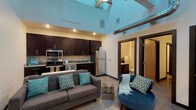 This two-story, 2-bedroom, 2-bathroom loft offers a dynamic blend of industrial character and modern comfort. The main level greets you with dramatically soaring ceilings, exposed ductwork, and polished concrete floors that lend an urban, warehouse-inspired aesthetic. A ceiling fan anchors the open-concept living area, which flows seamlessly into a well-appointed kitchen featuring dark espresso cabinetry, granite countertops, stainless steel appliances including a refrigerator, range, microwave, and dishwasher, and a casual dining setup with bar seating. A full bathroom with a granite-topped vanity and a tub-shower combination is conveniently located on this level. A staircase with a distinctive metal railing leads to the upper loft level, where warm hardwood flooring runs throughout. The primary bedroom is generously sized with a walk-in closet and access to a full en-suite bathroom, while the second bedroom features a cozy angled ceiling detail. Both bathrooms maintain a consistent design language with dark cabinetry and granite finishes. The overall ambiance balances an open, airy feel on the main level with a more intimate, private retreat upstairs.