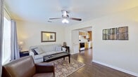 This two-floor residence offers a well-organized layout with functional living spaces across both levels. The living room serves as a welcoming centerpiece, featuring rich hardwood-style flooring, a ceiling fan with light fixture, and multiple windows dressed with blinds and curtain panels that allow natural light to fill the room. A decorative mirror and tasteful wall art complement the neutral-toned walls, while the open sightline into the kitchen creates a cohesive, connected feel.

The kitchen is equipped with warm honey-toned wood cabinetry extending both above and below the countertops, providing generous storage. White appliances include a range, dishwasher, and double-basin sink. The kitchen opens directly into a dining area illuminated by a pendant chandelier, with a window overlooking the exterior. An in-unit washer and dryer are conveniently positioned within this same space.

The bedrooms offer a quieter retreat, each carpeted and naturally lit through windows with curtain panels. One bedroom features a wrought-iron bed frame and ornate area rug, while another offers plush carpeting and ample floor space. The bathroom includes a tub-shower combination, wood vanity, and hardwood-style flooring, completing this straightforward and practical home.