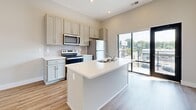 Located at 45 Diana Street in Memphis, TN, this thoughtfully designed one-bedroom, one-bathroom home offers a clean, modern aesthetic throughout its efficiently utilized single-floor layout. The open-concept living and kitchen area serves as the heart of the home, anchored by a central island with a white quartz countertop and integrated sink. The kitchen is well-appointed with gray shaker-style cabinetry, a subway tile backsplash, and a full suite of stainless steel appliances, including a refrigerator, electric range, and over-the-range microwave. Large sliding glass doors and multiple windows flood the living area with natural light and offer outdoor views, while a ceiling fan adds comfort overhead. Warm hardwood-style flooring runs throughout, complementing the neutral gray and white color palette. The entry foyer features a classic paneled front door flanked by windows, creating a welcoming first impression. The bedroom is generously proportioned, with elevated ceilings, dual windows, and direct access to a dedicated closet. The bathroom includes a glass-enclosed walk-in shower with marble-style tile. A dedicated laundry area houses a full-size washer and dryer, adding everyday convenience to this well-rounded home.