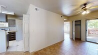 This well-organized single-story residence offers 1 bedroom and 2 bathrooms across a compact yet functional floor plan. Tile flooring runs throughout the entire unit, providing a clean, cohesive look from room to room. The entrance leads into an open layout connecting the dining area and kitchen, where a peninsula-style breakfast bar separates the two spaces. The kitchen is equipped with dark wood cabinetry, light countertops, a built-in microwave, and an electric range, offering ample storage and prep space. A pendant light fixture over the dining area adds a focused accent. The bedroom is a comfortable, well-proportioned space highlighted by a ceiling fan with a light kit and a distinctive arched window that allows generous natural light to fill the room. A large picture window in another area of the unit frames an outdoor view, further brightening the interior. The hallway connects the bedroom and bathrooms efficiently, with panel-style doors throughout. The full bathroom features a tub-shower combo with white tile accented by decorative red diamond inlays, a dark wood vanity with a light countertop, and a large mirror. The textured ceilings and neutral wall tones throughout contribute to a clean, move-in-ready atmosphere.