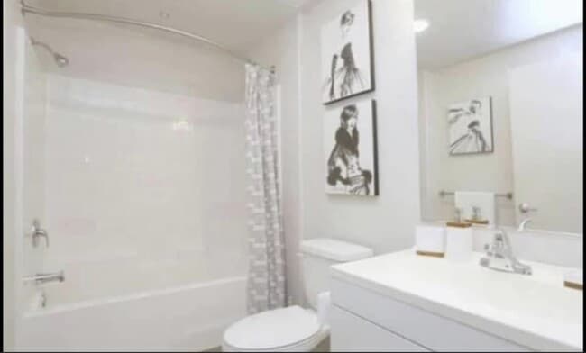 Bathroom with white fixtures and cabinets at City Plaza Apartments in Escondido, California. - City Plaza Apartments