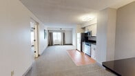 This well-appointed 2-bedroom, 4-bathroom single-floor residence offers a practical and comfortable layout with a clean, neutral aesthetic throughout. The open-concept living, dining, and kitchen area serves as the heart of the home, featuring a seamless transition between carpet and hardwood-style flooring. The kitchen is equipped with stainless steel appliances, including a refrigerator, microwave, and dishwasher, complemented by white cabinetry and a dark granite countertop. A window with draping curtains allows natural light to fill the living area.

Both bedrooms are generously sized and finished with patterned carpet flooring and neutral-toned walls. The primary bedroom features a ceiling fan with integrated lighting and a window with curtains, while framed artwork adds a decorative touch throughout. Each bedroom connects conveniently to the bathroom facilities.

The bathrooms are finished with large-format tile flooring and feature clean white fixtures. One bathroom highlights a floating vanity with a dark granite countertop, a backlit mirror with wall sconces, and a separate water closet. Additional bathrooms include a shower-tub combination with a grab bar. A dedicated closet provides supplemental storage. The overall ambiance is understated and functional, with a consistent neutral palette throughout.