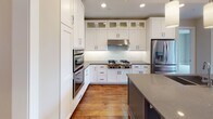 Located at 2622 W Lake St in Minneapolis, MN, this single-floor residence showcases a thoughtfully designed open-concept layout with high-end finishes throughout. Rich hardwood flooring flows through the main living and kitchen areas, anchoring the space with warmth and character.

The gourmet kitchen is a standout feature, equipped with stainless steel appliances including a gas cooktop, double wall ovens, and a french door refrigerator. Crisp white shaker cabinetry reaches to the ceiling, complemented by a subway tile backsplash, quartz countertops, and a large center island with a double sink and pendant lighting above. A tray ceiling with cove lighting adds architectural depth to the kitchen and dining area.

The primary bedroom suite offers plush carpeting, a tray ceiling with ceiling fan, and floor-to-ceiling windows with outdoor views. The en suite primary bathroom is generously appointed with rich wood cabinetry, a dual vanity with quartz countertops, a glass-enclosed walk-in rainfall shower, a soaking tub, and tile flooring — with direct access to a spacious walk-in closet. An additional carpeted bedroom connects to its own bathroom, and a sleek powder room with a vessel sink and wood-framed mirror serves guests. The overall ambiance is modern, refined, and move-in ready.