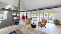 Located at 444 Saratoga Ave in Santa Clara, CA, this thoughtfully designed single-floor space offers a generous and versatile layout ideal for gathering and socializing. The open living area features soaring vaulted ceilings with striking exposed dark beams, light hardwood flooring, and a sophisticated contrast of dark slate-gray accent walls against crisp white surfaces. Curated wall-mounted shelving, framed artwork, and lush greenery add warmth and personality throughout.

The dining and lounge area is lined with expansive floor-to-ceiling windows that flood the space with natural light and offer serene views of the surrounding mature trees and outdoor patio. Tufted burgundy banquette seating runs along the windowed wall, complemented by mid-century-inspired wood and leather chairs arranged around bistro-style tables — creating an inviting café-like atmosphere.

The modern kitchen is equally impressive, featuring sage green walls, deep teal subway tile backsplash, white upper cabinetry with brass hardware, light wood lower cabinets, a large center island with a marble-look countertop and cooktop, stainless steel appliances, and a stainless range hood. Additional rooms provide flexible space for private meetings or activities. Throughout, the design balances contemporary aesthetics with functional, welcoming details.