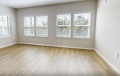 This contemporary 1,070 square foot apartment offers a harmonious blend of style and functionality. The open-concept layout seamlessly integrates the living room and kitchen, creating a spacious and inviting atmosphere. The kitchen boasts sleek white cabinetry, stainless steel appliances, and a large central island, perfect for meal preparation and casual dining.

Both bedrooms are generously sized, with the primary bedroom measuring 220 square feet. Large windows in each room flood the space with natural light, while plush carpeting adds comfort underfoot. The bathrooms feature modern fixtures, including a spacious vanity with ample storage in the main bathroom.

Throughout the apartment, a neutral color palette of whites and light grays creates a bright, airy ambiance. The living areas and kitchen are adorned with warm wood-tone flooring, adding a touch of natural elegance. Recessed lighting and stylish pendant fixtures provide layers of illumination.

Additional features include a ceiling fan for improved air circulation, window blinds for privacy, and multiple closets for storage. The apartment's thoughtful design maximizes space efficiency while maintaining a sense of openness, making it an ideal home for modern living.