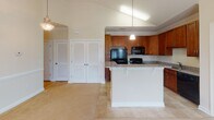 Located at 1000 Palisades Circle in Asheville, NC, this single-floor residence offers a well-designed open layout that connects the kitchen and living areas seamlessly. The kitchen is equipped with warm-toned cherry cabinetry, granite countertops, black appliances including a refrigerator, range, built-in microwave, and dishwasher, along with a peninsula that provides additional counter space and casual seating. Tile flooring runs throughout the kitchen, transitioning to plush neutral carpeting in the living and bedroom areas.

The living space benefits from vaulted ceilings and a ceiling fan, creating an airy atmosphere. French doors open to an outdoor area, allowing natural light to flow in alongside views of the surrounding landscape. Additional windows throughout the space further enhance brightness.

The bedrooms are comfortably sized, each featuring ceiling fans, neutral carpet, and windows with outdoor views. Louvered double doors provide convenient closet access in the main living area. The bathrooms are finished with granite-topped cherry vanities, tile flooring, and a tub-shower combination. Consistent use of granite countertops and cherry cabinetry throughout the home creates a cohesive and polished aesthetic.