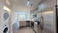 Located at 5500 Home Valley Dr in Raleigh, NC, this single-floor residence offers a thoughtfully designed open-concept layout with contemporary finishes throughout. The kitchen is a standout feature, showcasing light gray textured cabinetry, white quartz countertops, a classic subway tile backsplash, and a full suite of stainless steel appliances including a range, microwave, dishwasher, and refrigerator. A peninsula with an undermount sink and pendant lighting above creates a natural division between the kitchen and the expansive living area, which flows seamlessly underfoot with durable wood-style flooring. The living space benefits from generous natural light through large windows that frame outdoor views. The bedroom is a comfortable retreat featuring plush carpeting, a ceiling fan, and multiple windows that fill the room with daylight. A large walk-in closet with built-in wire shelving and ample storage accompanies the bedroom. The full bathroom is finished with large-format tile flooring, a wood-toned vanity with white countertop, a full tub-shower combination with tiled surround, and recessed lighting, completing the space with a clean, modern aesthetic.