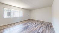 Located on Anza Avenue in Torrance, California, this single-floor, two-bedroom, two-bathroom residence offers a clean, functional layout designed for comfortable everyday living. The open living area is finished with light wood-style flooring that extends throughout the main spaces, while multiple windows dressed with vertical blinds allow natural light to fill the room. A textured ceiling adds a classic touch throughout the home. The kitchen is efficiently designed with white cabinetry, light countertops, a range with overhead ventilation, and matching wood-style flooring, providing a bright and practical cooking space. Both bedrooms feature soft wall-to-wall carpeting and sliding closet doors for storage, with windows that bring in natural light and views of the surrounding neighborhood. A hallway connects the private areas of the home. The two bathrooms are finished in a clean, minimal style — one features a floating vanity with a wide mirror and a towel bar, while the second includes a full tub-shower combination with white tile surround, a vanity, and illuminated mirror. Wood-style flooring is carried through both bathrooms, maintaining a cohesive aesthetic throughout the home. The overall ambiance is bright, neutral, and move-in ready.