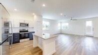 Located in Leander, TX, this two-story home offers 3 bedrooms, 3 bathrooms, and a well-designed layout spread across two floors. The main level features an open-concept kitchen and living area bathed in natural light from multiple windows. The kitchen is equipped with stainless steel appliances — including a refrigerator, range, and microwave — complemented by two-tone navy and white cabinetry, a granite-topped center island, and recessed lighting. The living room extends seamlessly from the kitchen, showcasing light wood-style flooring and a ceiling fan. A half bath on the main floor provides added convenience. Upstairs, the three bedrooms are carpeted and include ceiling fans and closets with louvered doors. The primary bedroom offers a comfortable, well-proportioned retreat. Three full bathrooms feature granite vanity tops, gray cabinetry, wood-style tile flooring, and tub-shower combinations with brushed nickel fixtures. A dedicated laundry area houses a stacked washer and dryer unit alongside built-in shelving for extra storage. Throughout the home, clean white walls, panel-style doors, and consistent finishes create a bright, modern aesthetic suited for everyday living.