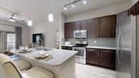 This single-story residence features 2 bedrooms, 3 bathrooms, and a thoughtfully designed open-concept layout. The kitchen is a standout highlight, boasting rich dark-espresso cabinetry, granite countertops, a large center island with an undermount sink, stainless steel appliances including a French door refrigerator and range, a tile backsplash, and elegant pendant lighting. Light wood-style flooring runs throughout the main living areas, complementing the neutral color palette and soaring ceilings that lend an airy, open feel.

The living room offers a welcoming atmosphere with a ceiling fan, wood-style flooring, and access to the outdoors through full-length glass doors framed by draping curtains. Both bedrooms are carpeted and feature ceiling fans, large windows with blinds, and generous closet space. The primary bedroom includes a walk-in closet with built-in shelving and hanging rods. The primary bathroom is elegantly finished with a dual-sink granite vanity, dark cabinetry, a glass-enclosed walk-in shower, and wood-style flooring. Additional bathrooms include a full soaking tub with tile surround. Two hallways and two closets provide ample circulation and storage throughout this efficiently organized home.
