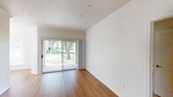 This two-bedroom, one-bathroom residence is thoughtfully laid out across a single floor, offering a comfortable and functional living environment. The main living area features warm hardwood-style flooring and elegant crown molding, lending a polished feel to the space. Sliding glass doors open to an outdoor view of mature trees and greenery, flooding the room with natural light and creating a seamless connection to the outdoors. The galley-style kitchen is efficiently designed with white cabinetry, light countertops, stainless steel appliances including a refrigerator, range, built-in microwave, and dishwasher, all complemented by the same warm hardwood-style flooring. Both bedrooms are carpeted for comfort and feature ceiling fans, with one bedroom offering a closet with built-in rods and ample storage space. The full bathroom is generously proportioned, showcasing an extended dual-sink vanity with a large mirror, well-lit by overhead fixtures, and hardwood-style flooring that ties the space together. Throughout the residence, neutral tones and clean lines create a bright, move-in ready atmosphere suited for a variety of lifestyles.
