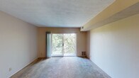 Located at 6827 Shenandoah Dr in Florence, Kentucky, this single-floor residence offers a practical and comfortable layout throughout. The living room is generously sized, featuring soft carpeting, neutral-toned walls, a ceiling fan, and a textured ceiling. A sliding glass door opens onto a private balcony that overlooks lush, tree-lined surroundings, bringing natural light and outdoor views into the space. The kitchen is efficiently laid out with warm wood-toned cabinetry, ample upper and lower cabinet storage, a double-basin sink, light countertops, and durable hardwood-style flooring. Appliances including a refrigerator, stove, and dishwasher are included. The two bedrooms are carpeted and feature neutral walls, windows with blinds that allow for natural light, and ceiling-mounted HVAC vents. Both rooms offer a comfortable sense of space suitable for various furniture arrangements. The unit includes two bathrooms: one featuring parquet-style tile flooring with a bathtub and vanity, and a second with mosaic tile flooring, a vanity with a lighted mirror, and a toilet. The overall design is straightforward and functional, with a consistent neutral color palette throughout, making the space move-in ready and easy to personalize.