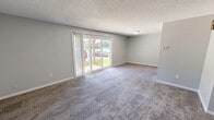 Located at 4281 Chestnut Ridge Road in Buffalo, New York, this single-floor, 930-square-foot unit offers a practical and comfortable layout with 2 bedrooms and 2 bathrooms. The spacious living room features neutral gray carpeting, soft gray walls, a textured ceiling, and large sliding glass doors that flood the space with natural light and provide views of the surrounding greenery. A decorative spindle partition separates the entry area, which features light wood-style flooring, from the carpeted living space. The kitchen is well-equipped with warm oak cabinetry, light countertops, wood-style flooring, and black appliances including a dishwasher, electric range, and refrigerator. The primary bedroom, at 160 square feet, includes dual sliding closets with mirrored panels and plush carpeting. The second bedroom also features carpet flooring and a bright window overlooking the exterior. Both bedrooms are finished with textured ceilings and gray walls. The two bathrooms include light wood-style flooring; one features a white vanity with a large mirror and a bathtub, while the other is highlighted by distinctive light blue tile surrounding the tub-shower combination.