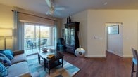 Located at 1555 Village Center Dr in Lakeland, Florida, this single-floor residence offers a thoughtfully designed layout that balances comfort and functionality. The living room is a welcoming focal point, featuring rich hardwood-style flooring, a ceiling fan, and large sliding glass doors that open onto a private balcony with outdoor seating and pleasant views of the surrounding greenery. The kitchen is well-appointed with rich wood cabinetry, granite-style countertops, stainless steel appliances, and ample storage and counter space. Adjacent to the kitchen, the dining area features wood flooring and a cozy atmosphere accented by soft teal walls and stylish décor. Two bedrooms provide comfortable retreats; the primary bedroom features plush carpeting, a window with natural light, and a walk-in closet, while the second bedroom offers a similarly serene environment with soft green accent walls and carpet flooring. Two bathrooms serve the home — one with a tub-shower combination and granite-topped vanity, and another with a single vanity sink. A dedicated in-unit laundry closet houses a full-size washer and dryer with built-in shelving above. Throughout, the home is finished with neutral tones and warm wood flooring, creating a cohesive and inviting atmosphere.