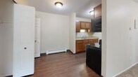 Located at 6129 Beechfield Dr in Lansing, Michigan, this single-floor unit offers a practical and functional layout throughout. The living area is generously proportioned, featuring neutral-toned carpet, cream-colored walls, and a large window dressed with vertical blinds that allows natural light to flow in while offering views of surrounding greenery. A baseboard heating system runs along the perimeter, and the entry door opens directly into this open space. The flooring transitions to hardwood-style planking as you move into the kitchen and dining area.

The galley-style kitchen is well-equipped, featuring warm wood cabinetry with ample upper and lower storage, light countertops, a double sink, and stainless steel appliances including a refrigerator, electric range, and over-the-range microwave. The adjacent dining area provides additional space and connects smoothly to the rest of the unit.

The bedrooms are carpeted and finished in the same neutral palette, each benefiting from natural light through windows with outdoor views. One bedroom features two side-by-side closets, offering substantial storage capacity.

The bathroom includes a full tub-shower combo with a white surround, a toilet, and a single-sink vanity with wood cabinetry, a large mirror, and durable vinyl plank flooring. The overall ambiance is clean, neutral, and move-in ready.