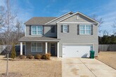 This well-appointed two-story home offers generous living space across two floors, providing ample room for comfortable living. The main level features an open-concept kitchen and living area, a dedicated dining room, and a welcoming entrance. The kitchen stands out with crisp white cabinetry, granite countertops, stainless steel appliances including a French door refrigerator and range, a central island with a sink, and recessed lighting — all complemented by warm hardwood-style flooring that flows throughout the home.

The upper floor hosts the majority of the five bedrooms, including a spacious primary suite. Bedrooms are bright and clean, featuring natural light from windows and ceiling fans where applicable. The home includes six full bathrooms finished with neutral tile flooring and tub-shower combinations. Eight closets are distributed throughout, offering exceptional storage, including walk-in closets with wire shelving systems.

Additional highlights include a dedicated laundry room equipped with a full-size washer and dryer, two hallways connecting the living areas seamlessly, and an attached garage with interior access. The consistent use of light neutral tones, clean white trim, and hardwood-style flooring gives the entire home a cohesive, modern aesthetic.