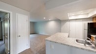This single-story, 3-bedroom, 2-bathroom home offers a practical and well-organized layout designed to maximize every square foot. The open-concept kitchen and living area serves as the heart of the home, where a peninsula with light granite-look countertops separates the kitchen from the carpeted living space. The kitchen is equipped with warm wood-toned cabinetry, black appliances including a refrigerator, range, and microwave, as well as wood-look flooring and a recessed ceiling detail that adds a subtle architectural touch. A skylight above the kitchen peninsula brings in additional natural light.

The living room is generously proportioned, featuring neutral carpet and a sliding glass door that opens to a green outdoor area, filling the space with natural light and offering easy outdoor access. The three bedrooms are carpeted and finished with neutral tones throughout. The spacious primary bedroom includes a walk-in closet with built-in shelving and a window overlooking the exterior. The two bathrooms each feature a tub-shower combo with brushed nickel fixtures. A connecting hallway ties the layout together efficiently. Overall, the home presents a clean, move-in-ready interior with consistent finishes throughout.