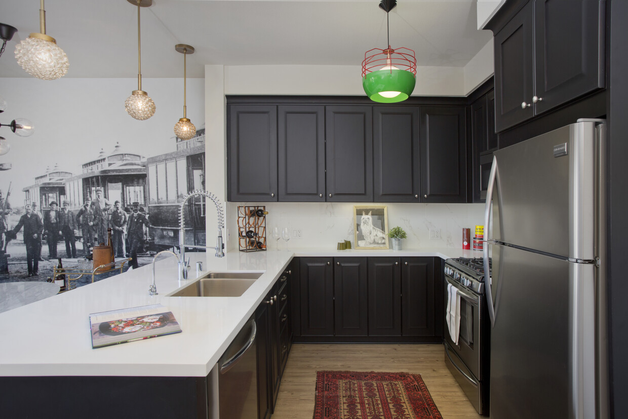 Kitchens with dark cabinetry, white quartz countertops, white tile backsplash, stainless steel appliances, and hard surface flooring - AVA Balboa Park