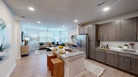 Located at 19025 Stuebner Airline Road in Spring, TX, this one-bedroom, one-bathroom unit offers a well-designed open-concept layout across a single floor. Light wood-tone flooring runs throughout, creating a cohesive and contemporary aesthetic.

The kitchen is a standout feature, equipped with stainless steel appliances including a French door refrigerator, a stainless range, and a microwave. Rich, dark taupe cabinetry with brushed gold hardware is complemented by a white subway tile backsplash and granite countertops. A central island with an undermount sink and seating for multiple stools serves as a functional gathering point that flows directly into the living area.

The living room receives ample natural light through large windows fitted with horizontal blinds, and a ceiling fan overhead promotes airflow and comfort. The space is open and versatile, accommodating both relaxation and workspace arrangements.

The bedroom is a calm, neutral retreat with a ceiling fan, a window for natural light, and direct access to a walk-in closet outfitted with wire shelving systems for organized storage.

The bathroom features a tub-shower combination with white subway tile surround, a dark vanity with granite countertop, and wood-tone flooring, maintaining the consistent design language found throughout the unit.