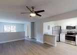 Located in Plantation, FL, this single-floor residence offers a clean, modern aesthetic with a thoughtfully open layout. Light wood-look flooring runs seamlessly throughout the main living areas, creating a cohesive and airy feel. The spacious living area is finished with neutral gray walls, white baseboards, a textured ceiling, and a ceiling fan, while a large window allows natural light to fill the room.

The open-concept design connects the living space directly to the kitchen, which is well-appointed with crisp white cabinetry, granite-style countertops, a kitchen island with a breakfast bar, and a full suite of stainless steel appliances including a refrigerator, range, microwave, and dishwasher. A window above the double-basin sink brings in additional natural light.

The bathroom is finished with tile flooring, a tiled tub-surround with a window, and a vanity topped with a granite-style countertop, complemented by brushed nickel fixtures. The overall palette of soft grays, whites, and warm wood tones gives the space a fresh, updated character. A wall-mounted AC unit and sliding glass door access are also present, adding both comfort and connectivity to the outdoors.
